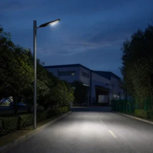 All-in-one LED solar street light installed over an industrial access road at dusk