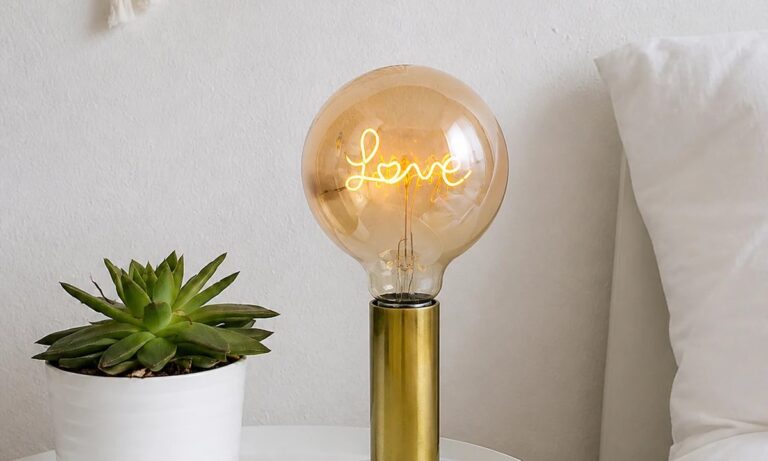 Decorative letter LED filament bulb glowing in a bedside setting